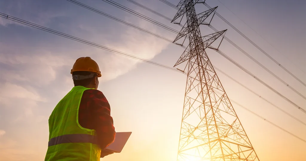 Electrical worker looking up at power lines